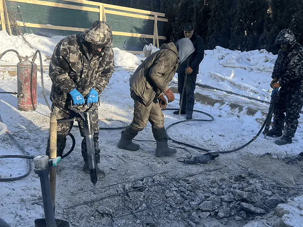 Бригада зимой разбивает бетон отбойными молотками на стройплощадке